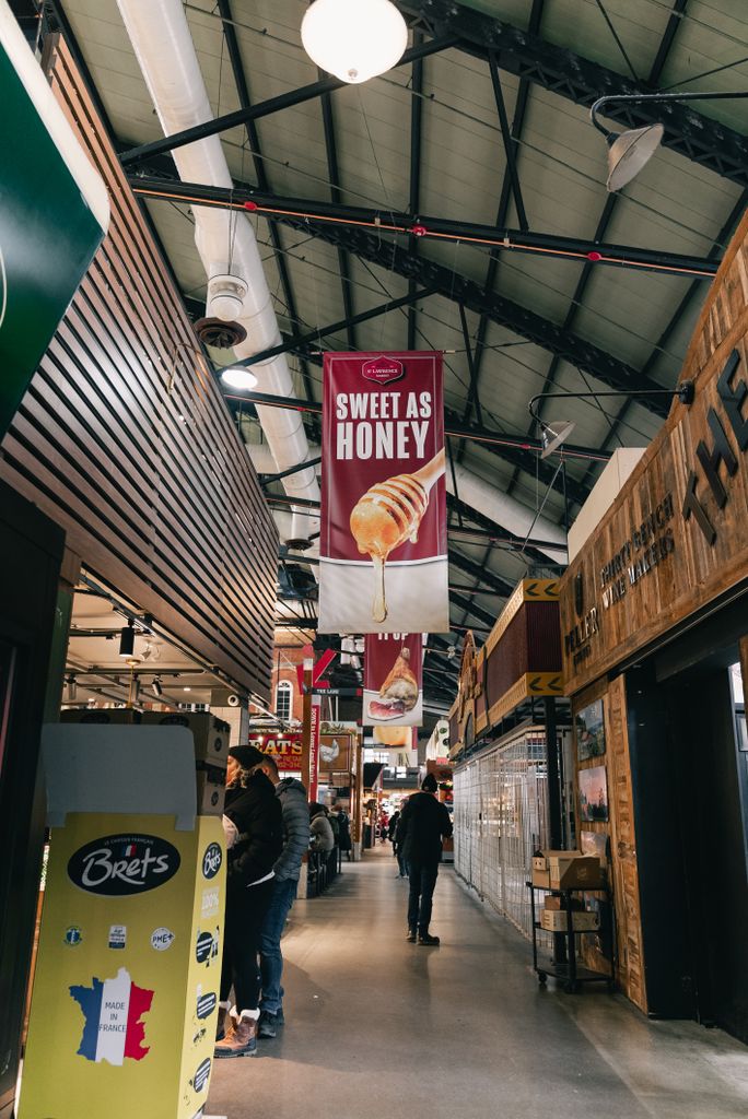 A vibrant indoor market scene with diverse stalls and a prominent 'Sweet as Honey' banner.